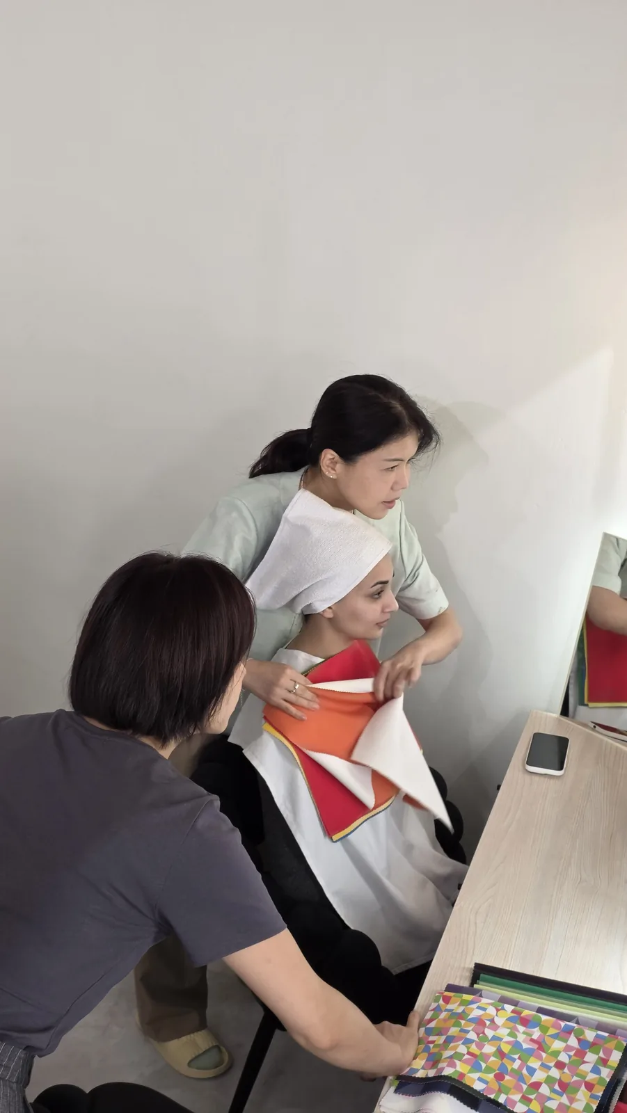 Consultant comparing warm color drapes during a Korean personal color analysis