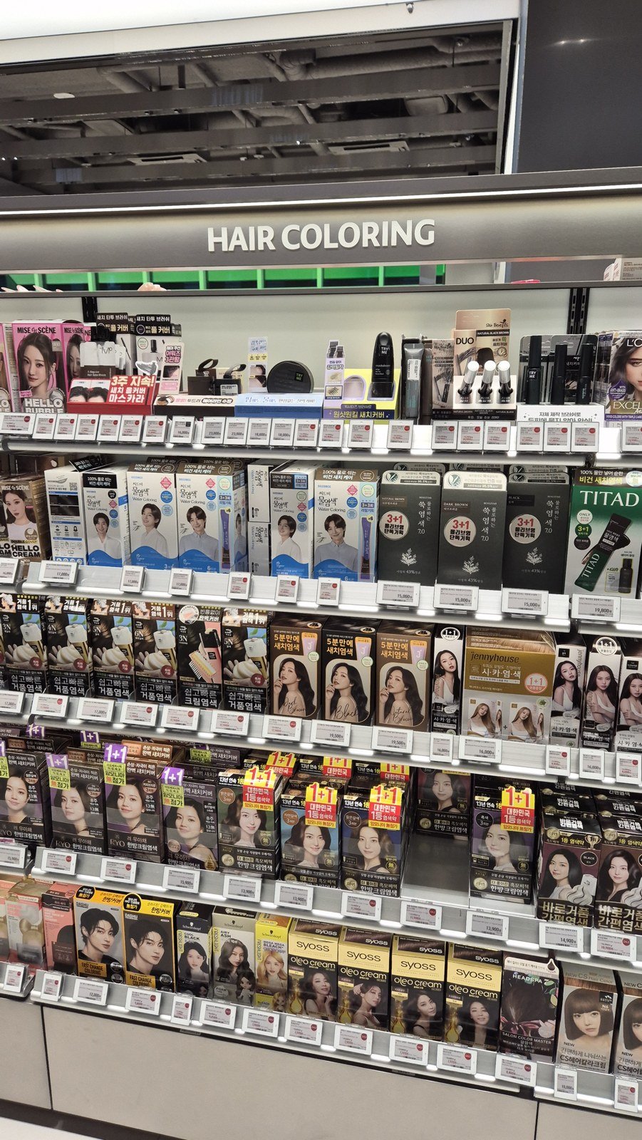 Boxed hair dye products beneath a Hair Coloring sign at Olive Young in Gangnam